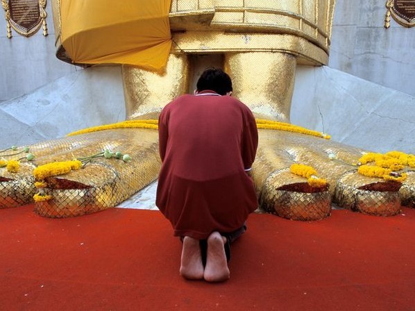 在曼谷的intharavihara寺院中,一个信徒跪在27.