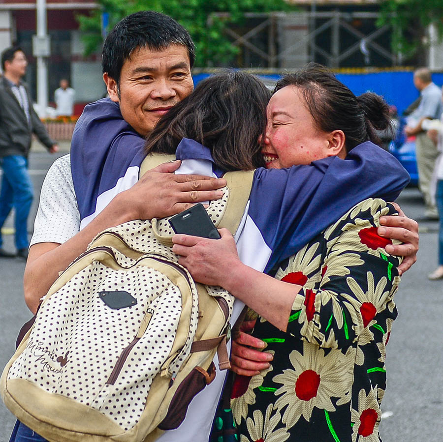 一名考生在进考场前与父母拥抱.