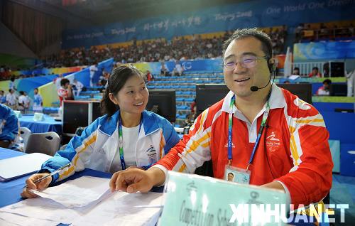 9月10日,来自天津体育学院的教师赵春英(前左)在残奥会举重赛场担任