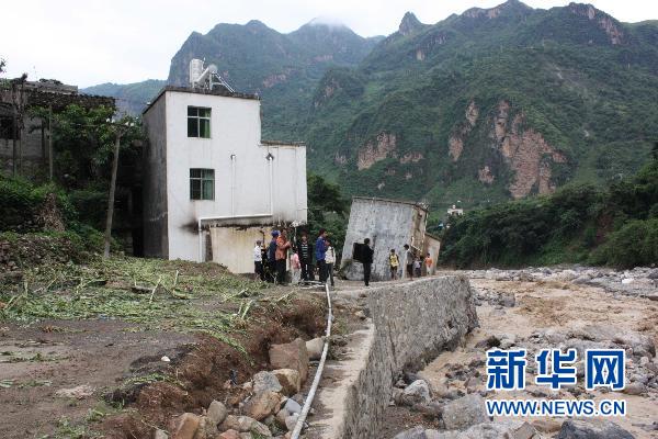 7月13日,雲南昭通市巧家縣小河鎮村民站在受損的房屋外.新華社發