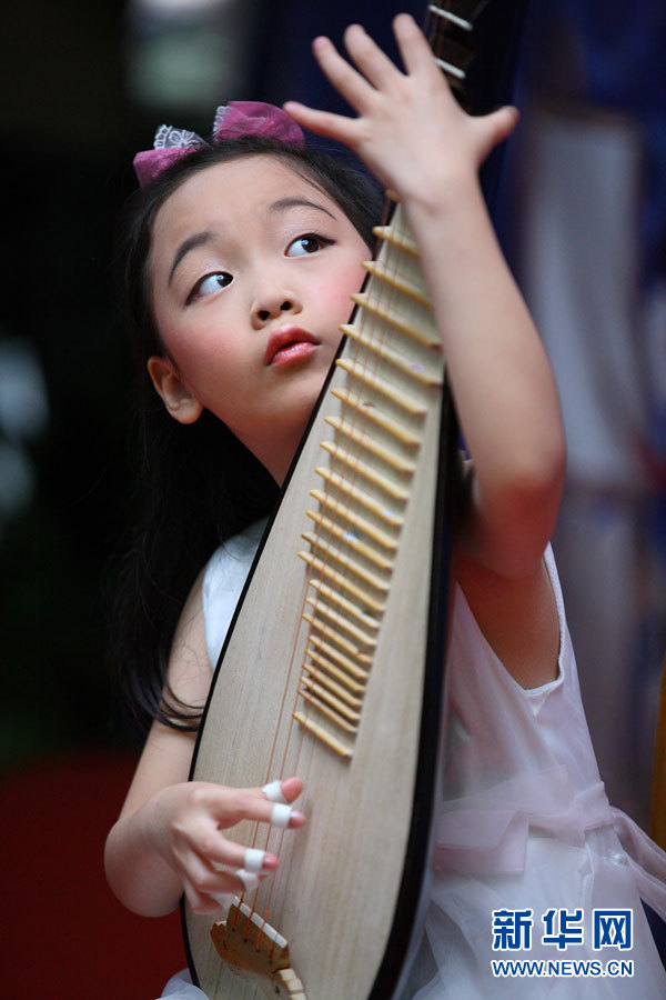 市青少年宫举行的庆祝"六一"汇报演出中,一名小朋友展示琵琶演奏才艺