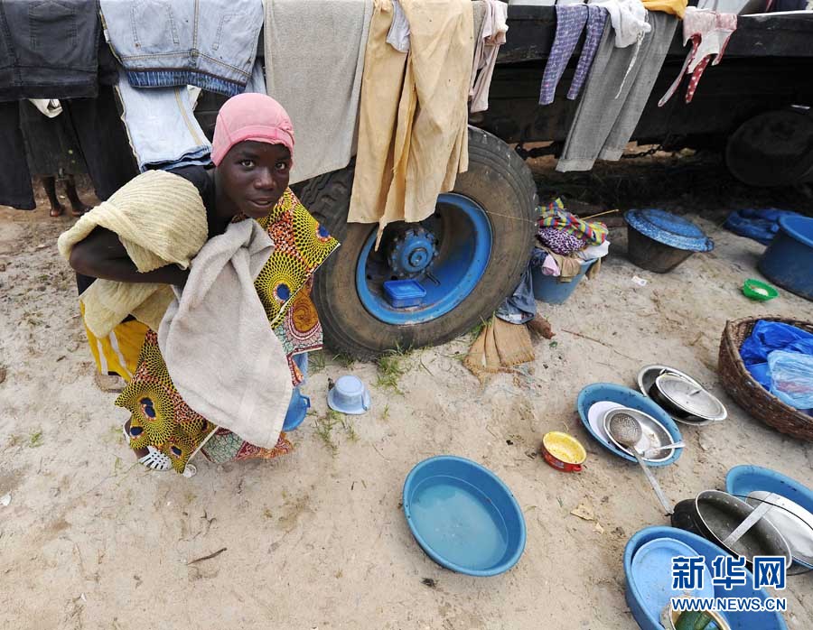 在科特迪瓦经济首都阿比让班热维尔区难民点,一名妇女在晾晒衣服