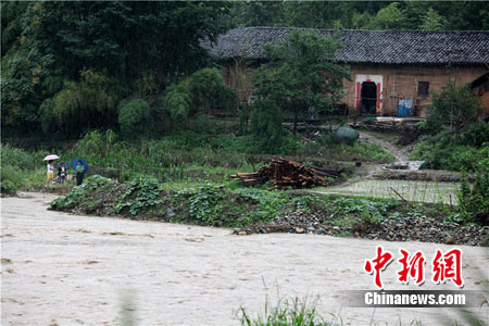 图为河道对面被困的群众和房屋。 赵渊盛 摄