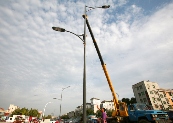 在县城浦源大道改造施工现场,施工人员昨天正忙着吊装节能路灯.