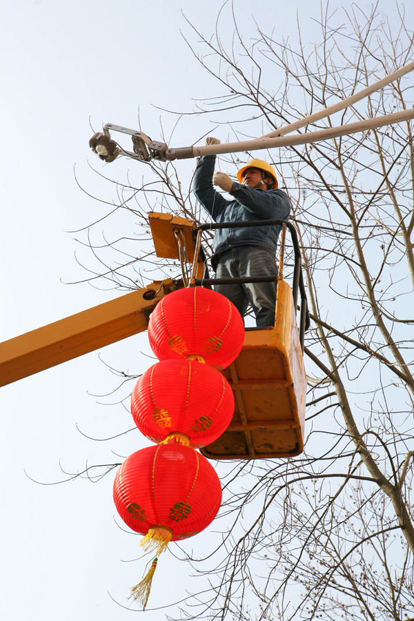 县供电局电气安装公司的施工人员,正在县城主街道两边悬挂大红灯笼,以