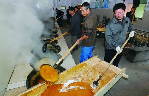 市义亭镇西楼村榨糖车间一溜排着9口大锅,榨糖师傅开始忙着熬制红糖