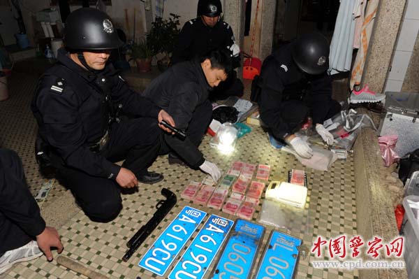 民警从制售毒贩家中搜查出的毒品,枪,毒资及假车牌.
