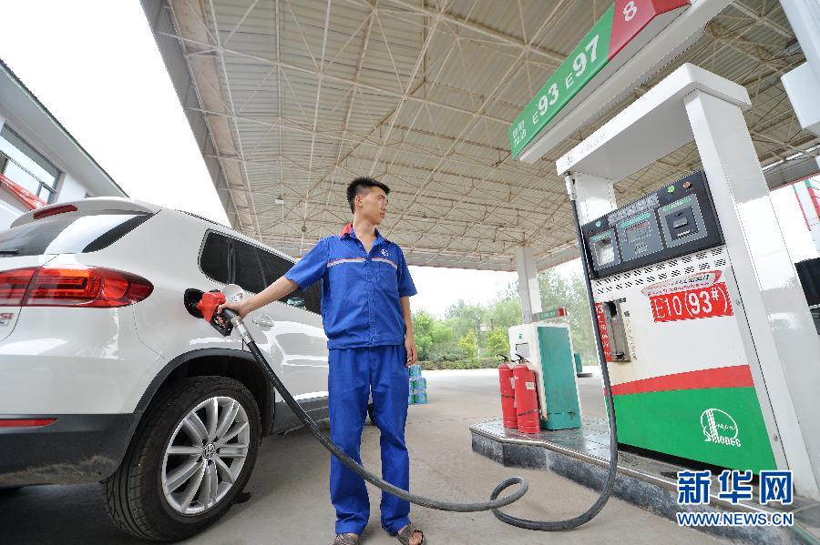 7月21日,河北保定一家加油站的工作人员在为机动车加油.