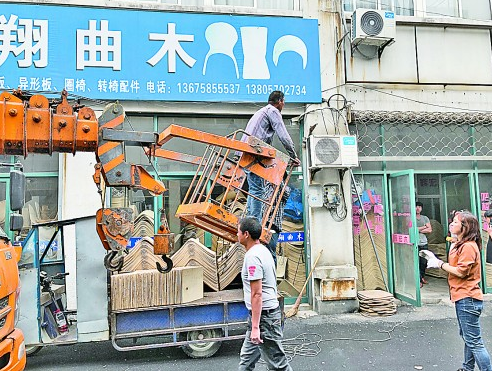 转椅市场里工作人员准备拆除破旧的广告