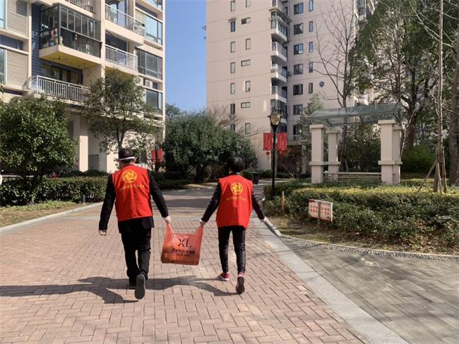 志愿者黄爱弟提着代买的菜走在小区里的身影,成为冬天里最暖心的背影