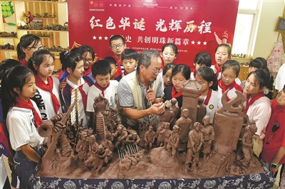 向学生们一边讲述自己刚创作完成的陶艺党史作品的心得体会,一边对